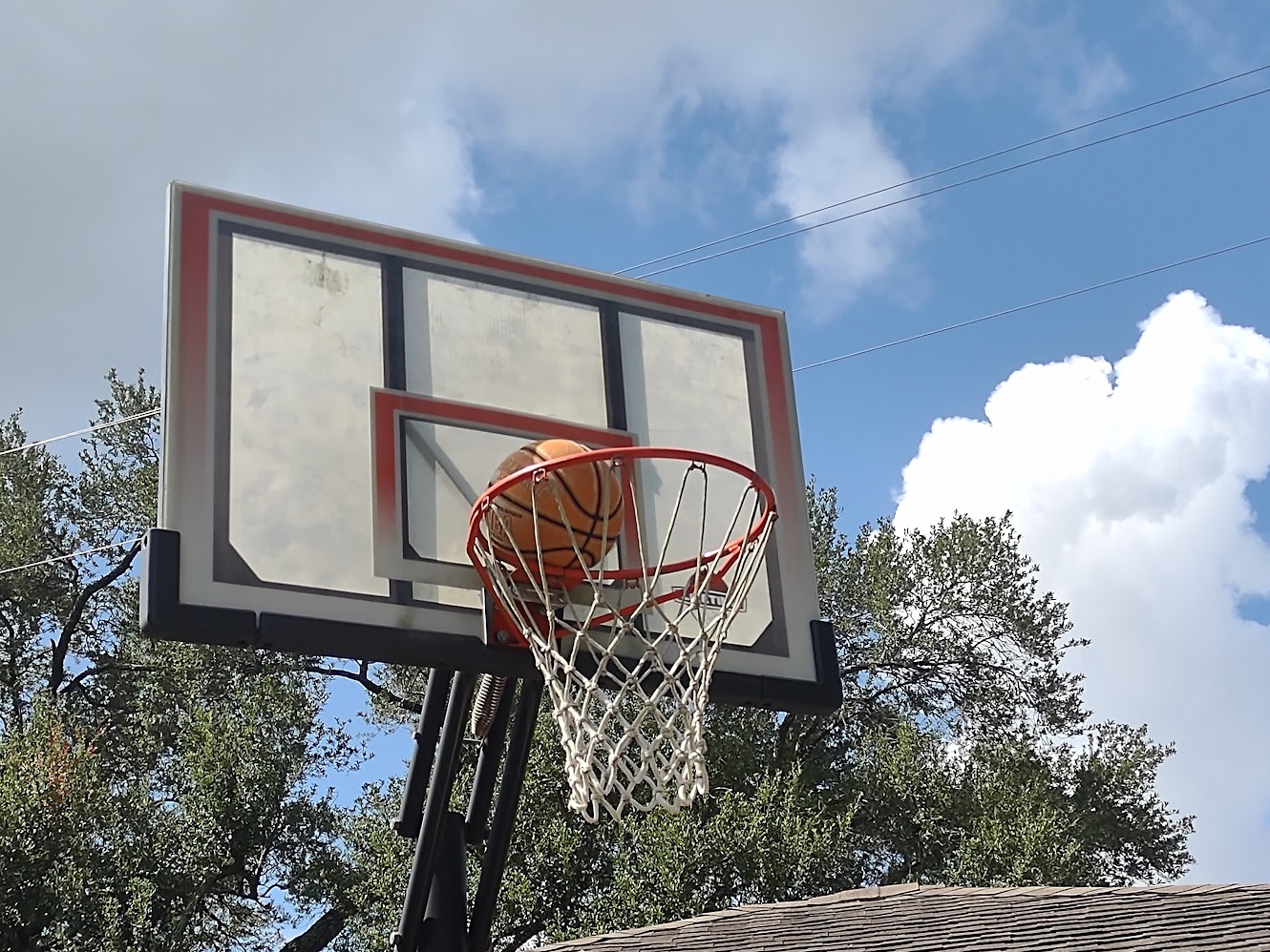 A basketball dropping through an outdoor hoop