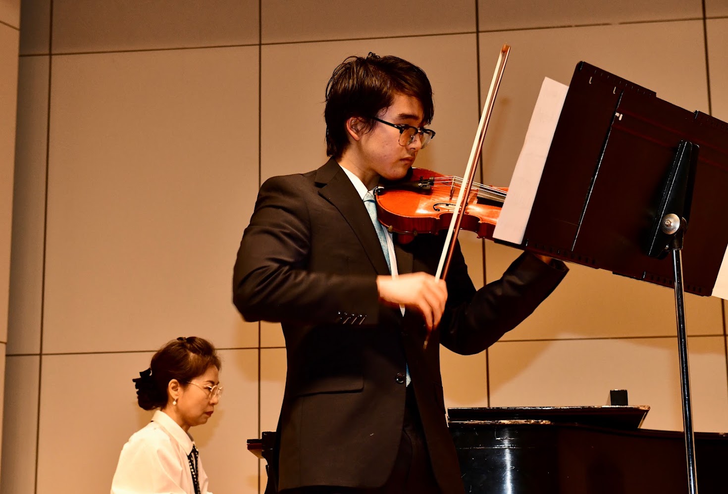 Feifan playing violin with a pianist accompanying