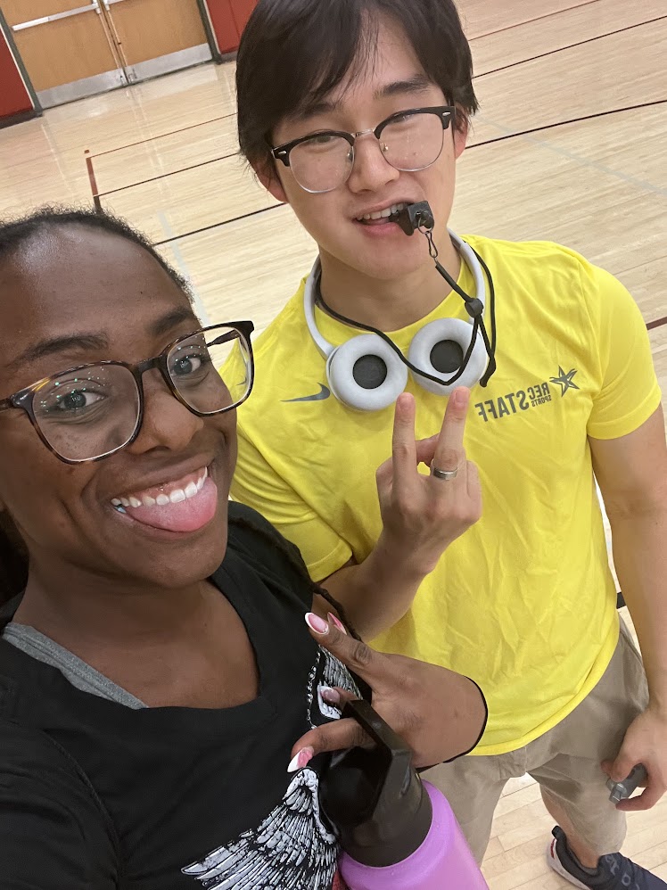 Feifan in a rec sports ref shirt with a whistle, next to a friend